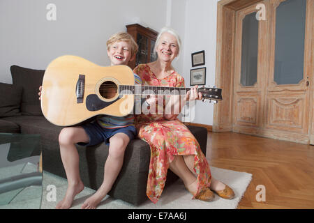 Glücklich Enkel und Oma mit Gitarre sitzt zu Hause auf sofa Stockfoto