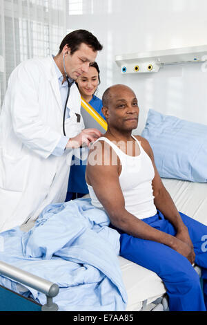 Arzt und Krankenschwester untersucht ein Patient sitzt auf einem Krankenhausbett Stockfoto
