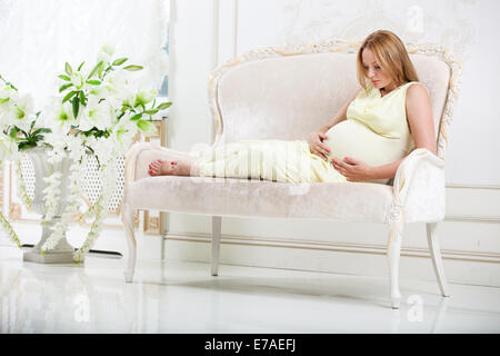 Schwangere Frau auf Couch zu Hause Stockfoto
