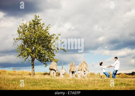 Junges Paar in der ukrainischen Stil Kleidung Spaß gegen alte Bienenstöcke Stockfoto