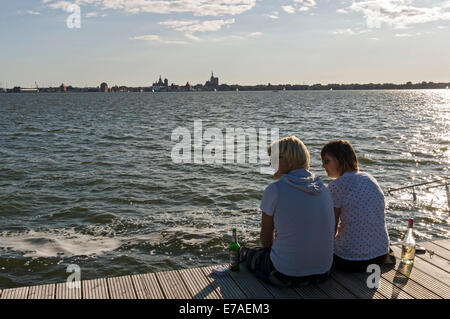 Junges Paar genießen den Blick über den Strelasund nach Stralsund von Altefähr auf der Insel Rügen, Mecklenburg-Vorpommern, Deutschland. Stockfoto