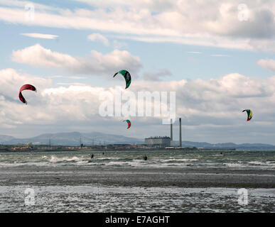 Vier Kitesurfern bei starkem Wind in der Schaum-Mündung mit Cockenzie Power Station und die Pentland Hills hinter üben. Stockfoto