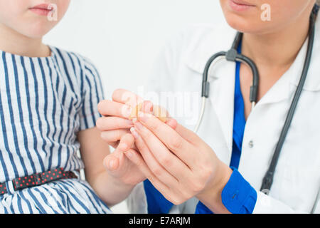 Arzt legt Pflaster auf Kind Finger. Stockfoto