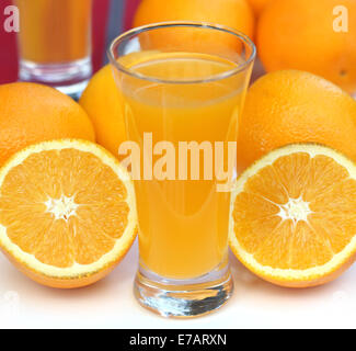 Orangen mit Glas Saft über weiß Stockfoto