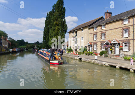 Schmale Boot Segeln auf der Grand Union Canal, UK; terrassenförmig angelegten Bungalows und Kanalmuseum auf der rechten Seite Stockfoto