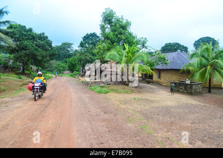 Ein Motorradfahrer durch ein Dorf im östlichen Sierra Leone Reisen Stockfoto