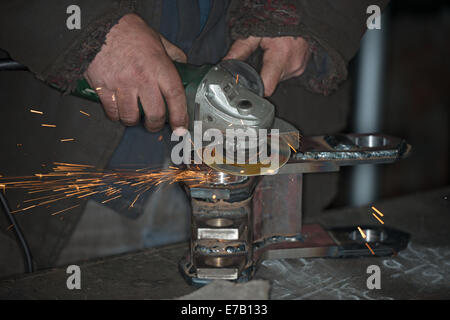 Ukrainische Arbeiter ist Schneiden von Metall mit Winkelschleifer, die Jet Funken macht. Stockfoto
