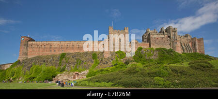 Panorama des riesigen und historischen Bamburgh Castle auf grasbewachsenen Hügel unter blauem Himmel in England Stockfoto