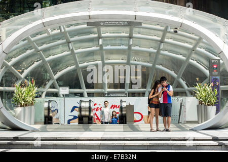 Fußgänger, die mit einer Rolltreppe ergeben sich aus den Untergeschossen der Ion Orchard Mall auf der Orchard Road in Singapur Stockfoto