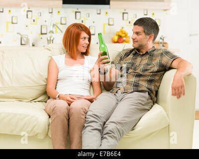 paar beim Gespräch sitzend auf Sofa, trinken Bier Stockfoto