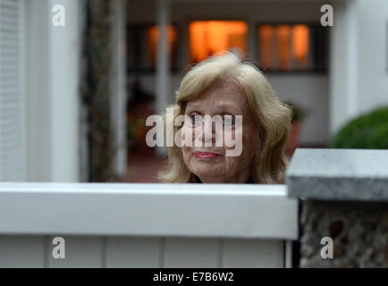 München, Deutschland. 11. September, 2014. Die Frau des verstorbenen deutschen Schauspieler und TV-Legende steht Joachim "Blacky" Fuchsberger, Gundula Fuchsberger im Gateway ihres Hauses wie der Körper des Mannes in Grünwald bei München, 11. September 2014 weggetragen wird. Fuchsberger starb im Alter von 87 in seinem Haus am 11. September 2014. Foto: ANDREAS GEBERT/Dpa/Alamy Live-Nachrichten Stockfoto