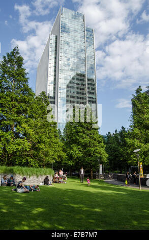 LONDON, UK 1. Juli 2014: Sonnenanbeter in Jubilee Park übersehen von Clifford Chance zentrale London Docklands. Stockfoto