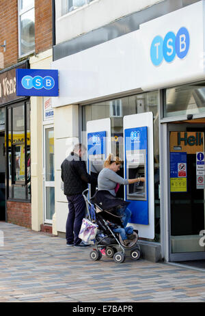 Junger Mann und Frau mit zwei Geldautomaten außerhalb einer Niederlassung der TSB Bank Stockfoto