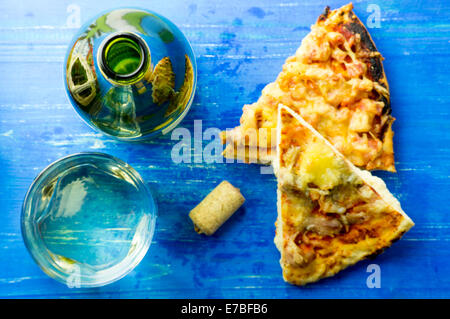 Weißwein und Pizza und eine Flasche aus Glas auf einem blauen Hintergrund von oben Stockfoto