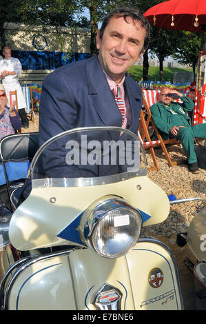 Quadrophenia-Star Phil Daniels eröffnete das Goodwood Revival, indem er eine Gruppe von Mods um die Strecke führte. Nach der Fahrt auf dem Motorroller sitzen Stockfoto