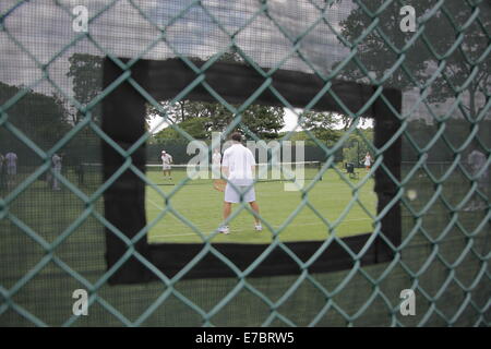 Menschen, die Tennis spielen, gesehen durch eine Öffnung in schützenden Fechten, USA, 2014, © Katharine Andriotis Stockfoto