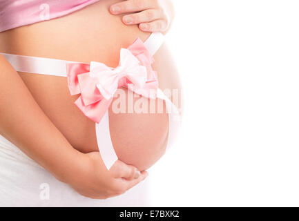 Es ist ein Mädchen, Körperteil der schwangeren Frau isoliert auf weißem Hintergrund, großer Bauch mit rosa Schleife drauf Stockfoto