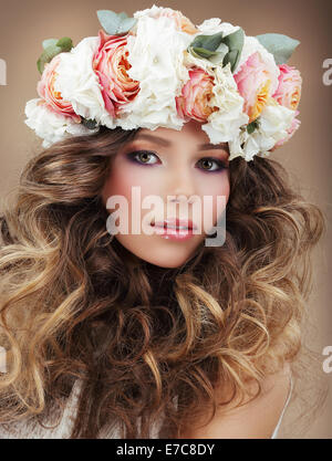 Romantische Frau in Kranz von Blumen mit perfekter Haut und krauses Haar Stockfoto