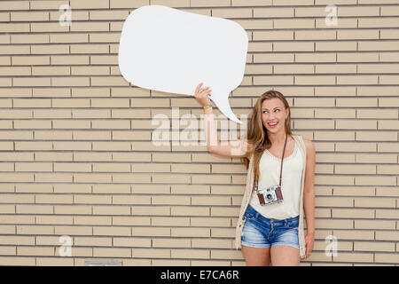 Schöne und junge Teenager halten eine Gedankenblase vor einer Mauer Stockfoto