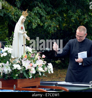 Fallowfield, Manchester, UK 13. September 2014 Fr Simon Stamp, ein junger Priester aus Accrington, segnet Medaillen der Muttergottes. Die Legion Mariens hält seinen 41. Annual Rosenkranz Kreuzzug in Platt Fields Park. Rund sechzig Katholiken besuchen, rezitieren den Rosenkranz, singen Lieder und mit einer kleinen Prozession. Rosenkranz Kreuzzug Manchester, UK Stockfoto