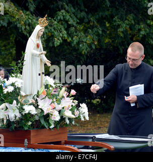Fallowfield, Manchester, UK 13. September 2014 Fr Simon Stamp, ein junger Priester aus Accrington, segnet Medaillen der Muttergottes. Die Legion Mariens hält seinen 41. Annual Rosenkranz Kreuzzug in Platt Fields Park. Rund sechzig Katholiken besuchen, rezitieren den Rosenkranz, singen Lieder und mit einer kleinen Prozession. Rosenkranz Kreuzzug Manchester, UK Stockfoto