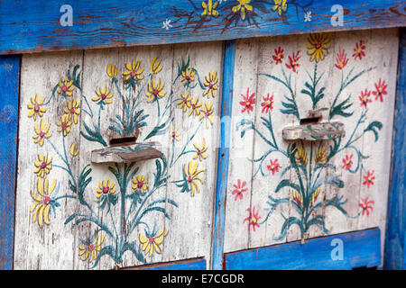 Bemalte alte Bienenstöcke und Bienenstöcke, dekorative Blumenmotive auf Holzbienenstock Stockfoto