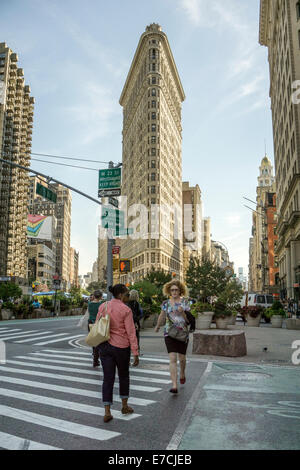 elegantes Profil von 1902 Flatiron Gebäude beherrscht Skyline überragt Fußgänger an Kreuzung von Broadway & 5th Avenue Stockfoto