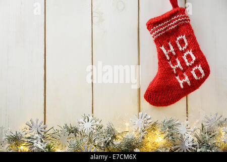 Tanne Zweig mit Weihnachtsbeleuchtung und Weihnachtsmann rot Strumpf auf Holz Hintergrund Stockfoto