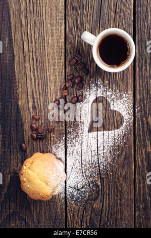 Tasse Kaffee und Muffin auf Vintage Holz-Hintergrund mit Herz Stockfoto