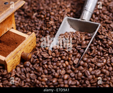 Antike Kaffeemühle mit gemahlenen Kaffee in Schaufel auf Bohnen Stockfoto
