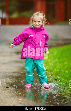 Glückliches kleine Mädchen spielt in einer Pfütze Stockfoto