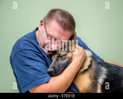 Junger Mann umarmt und Consolating seinen Hund Stockfoto