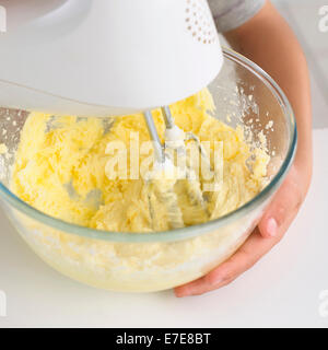 Boy Butter und Zucker zusammen mit elektrischen Schneebesen mischen Stockfoto
