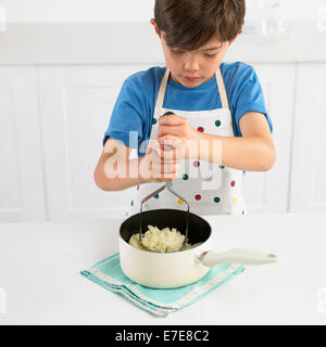 Junge Maischen Kartoffeln in einen Topf geben, 7 Jahre Stockfoto