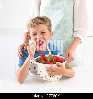 Kleiner Junge aus einer Schüssel Erdbeeren essen Stockfoto