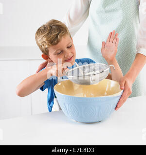 Mehl in die Rührschüssel sieben junge Stockfoto