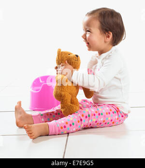 Kleinkind Mädchen mit Teddy saß neben Töpfchen, 1,5 Jahre Stockfoto