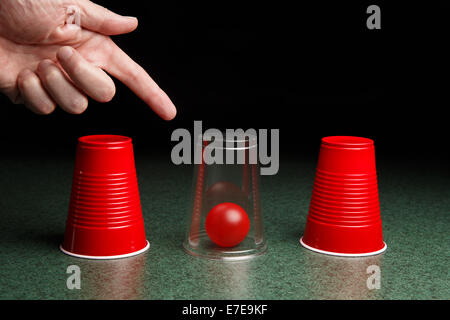 Leben ist einfach, wenn Sie die Antworten kennen.  Lage des roten Ball wird durch klare Tasse und zeigende Hand aufgedeckt.  Kopieren Sie Raum. Stockfoto