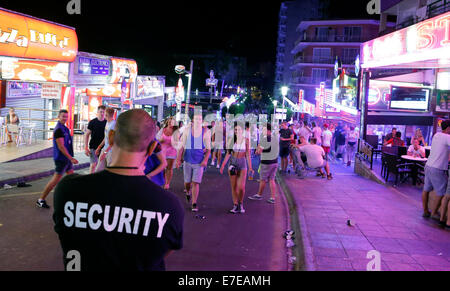 Ein Wachmann beobachten junge britische Touristen in Punta Ballena in Magaluf auf der spanischen Insel Mallorca genießen Stockfoto