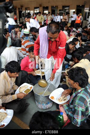 Neu-Delhi, Indien. 15. September 2014. Neu-Delhi, Anand Vihar Bahnhof in Neu-Delhi. 15. Sep, 2014. Ein Arbeiter von Indian Railway gibt Nahrung zu einer Gruppe von gestrandeten Menschen, meist aus östlichen indischen Bundesstaat Bihar, nach ihrer am Bahnhof in Neu-Delhi, Anand Vihar am 15. September 2014 Ankunft. Menschen wurden aus ihren Häusern in Flut betroffenen Bereich in Indien vertrieben. Bildnachweis: Partha Sarkar/Xinhua/Alamy Live-Nachrichten Stockfoto
