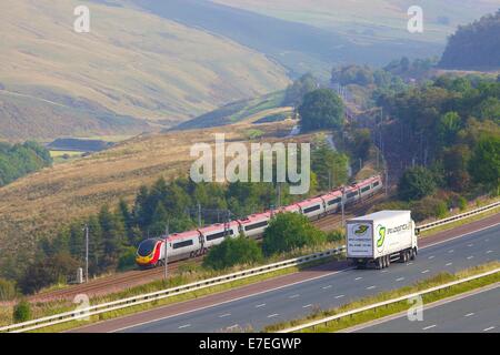 Klasse 390 Pendolino Jungfrau Bahn vorbei an der Autobahn M6 im Tal Flusses Lune. Howgills, Cumbria, West Coast Main Line, UK. Stockfoto