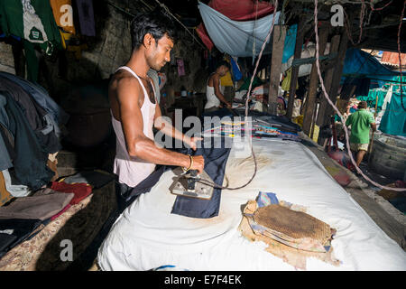 Ein Arbeiter ist Bügeln Wäsche bei Mahalaxmi Dhobi Ghat, Wäsche Bezirk von Mumbai, Maharashtra, Indien Stockfoto