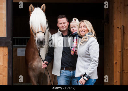 Junge Familie stehend mit einem Tyrolean Haflinger vor einem Stall, Nord-Tirol, Österreich Stockfoto