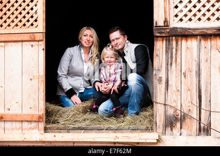 Junge Familie sitzt in der Scheune, Nord-Tirol, Österreich Stockfoto