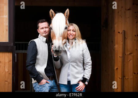 Junges Paar mit einem Tyrolean Haflinger vor einem Stall, Nord-Tirol, Österreich Stockfoto