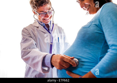 Arzt WomanÕs schwangeren Bauch hören Stockfoto