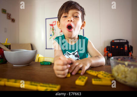 Gemischte Rassen junge spielt mit Dominosteinen am Küchentisch Stockfoto