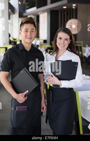 Kellner und Kellnerin lächelnd zusammen im restaurant Stockfoto