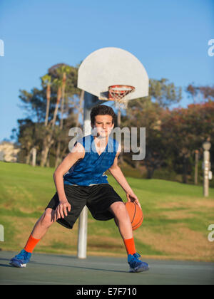 Kaukasische Basketballspieler Ball auf Platz dribbeln Stockfoto