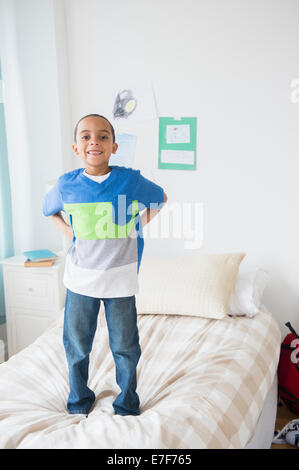 Gemischte Rassen Junge stand auf Bett Stockfoto